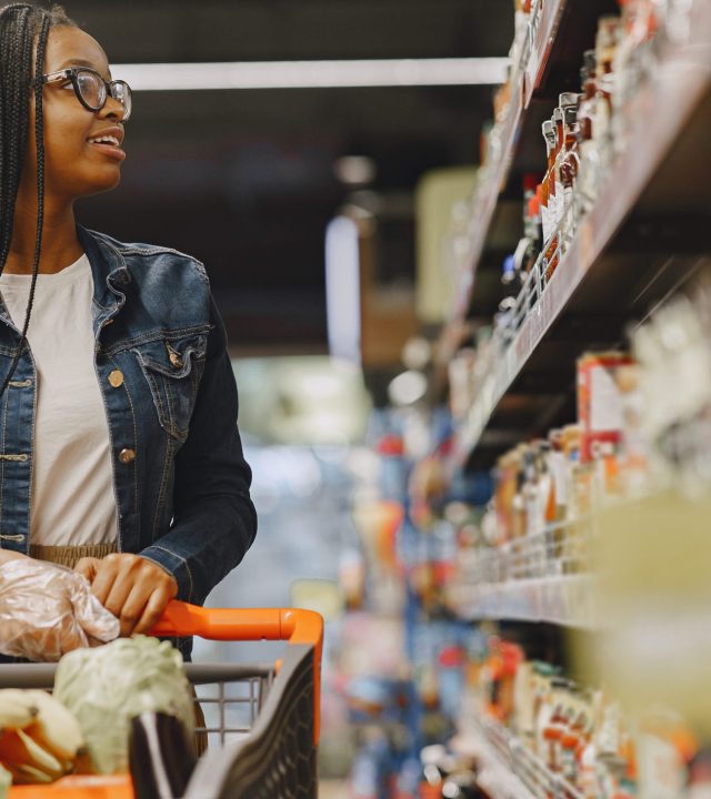 African woman with shopping cart. Girl in a supermarket.